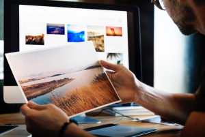 image of a man taking a look at a photograph in front of a computer screen